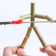 Hand holding a bamboo fire-starting device with a lit wick on a white background