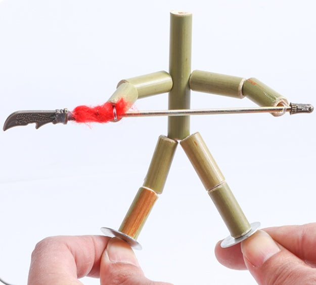 Hand holding a bamboo fire-starting device with a lit wick on a white background