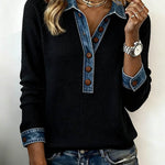 Person wearing a black sweater with denim collar and cuffs on a plain background