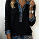 Person wearing a black sweater with denim collar and cuffs on a plain background