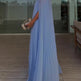 Woman in a light blue dress holding a clutch in an indoor setting.