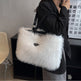 Person holding a white fluffy handbag indoors.