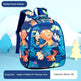 A children's backpack with a colorful cartoon animal print featuring lions, monkeys, foxes, and dinosaurs on a dark blue background. The image includes promotional text overlays at the top and bottom, and stylized blue and yellow tree props on a light blue background.