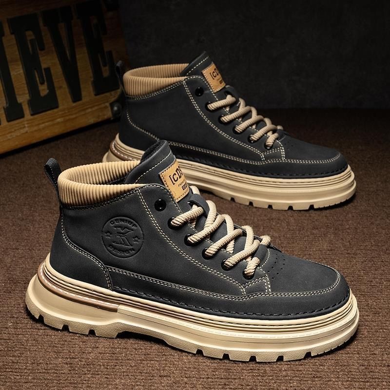 Pair of black and beige high-top sneakers on a brown surface