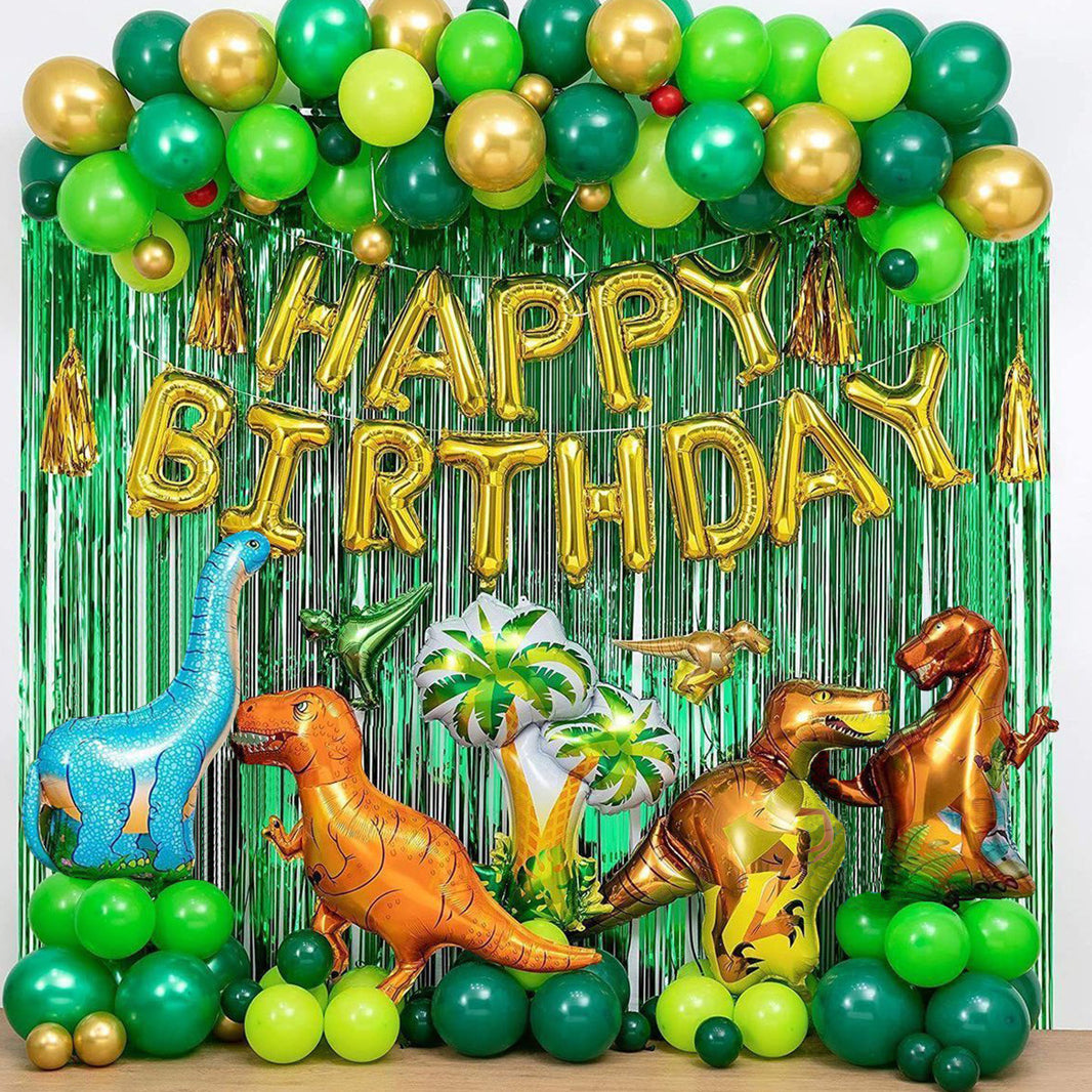 Birthday party setup with dinosaur balloons, green and gold balloons, and 'Happy Birthday' banner.