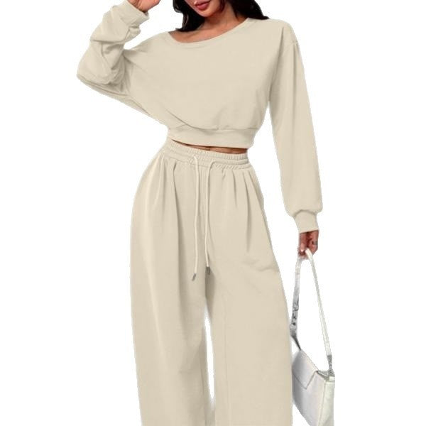 Woman wearing a beige long-sleeve top and wide-leg pants on a white background