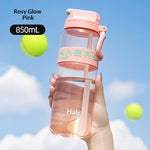 Hand holding a pink Hals water bottle with tennis balls in the background