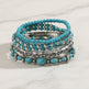 Stack of turquoise beaded bracelets with silver accents on a wooden surface