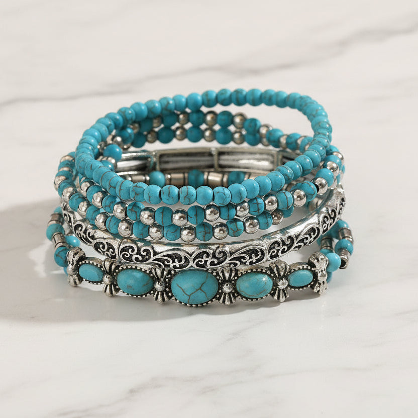 Stack of turquoise beaded bracelets with silver accents on a wooden surface