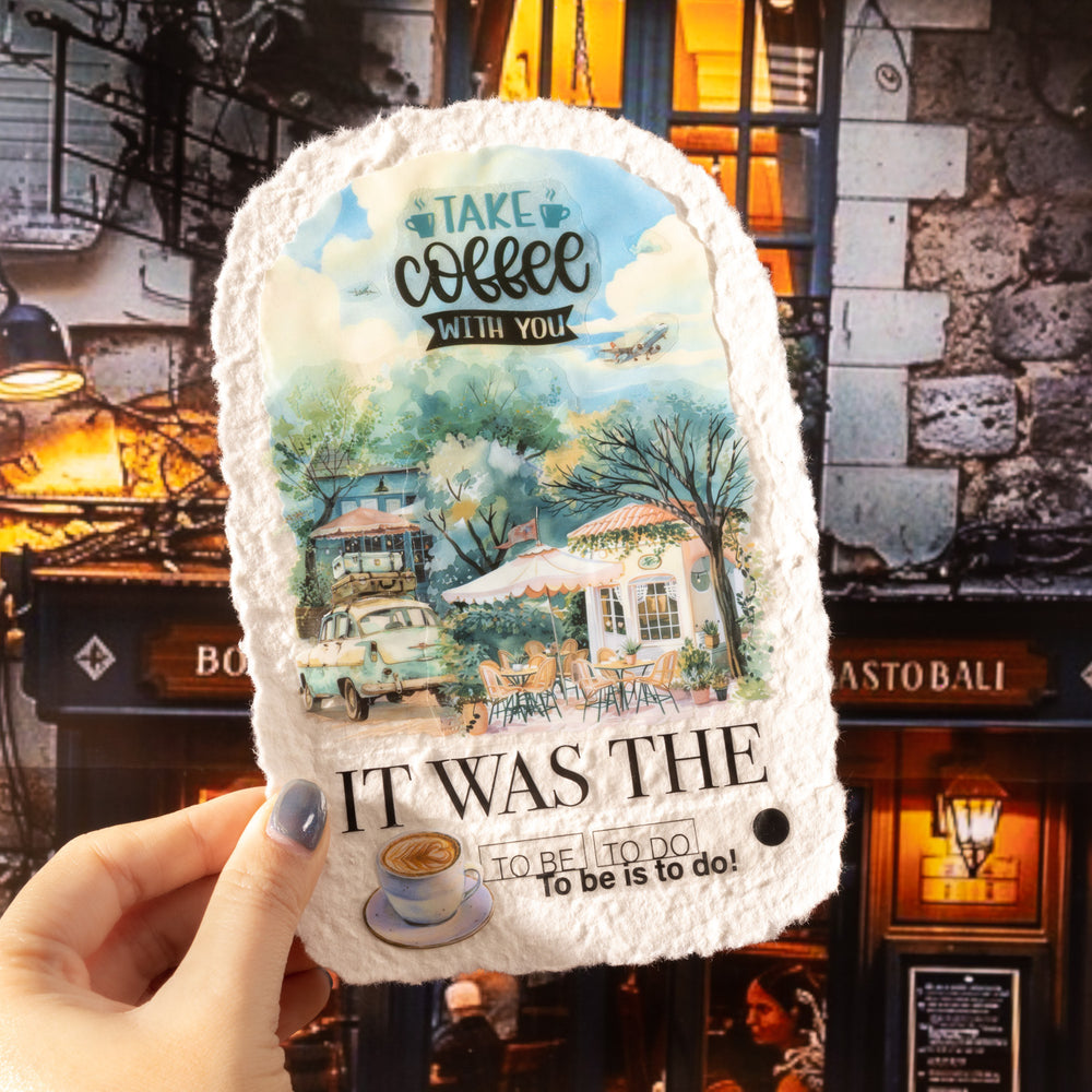 Product packaging with scenic design and text held in front of a cozy café setting