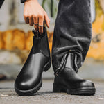 Person wearing black Chelsea boots with a blurred background