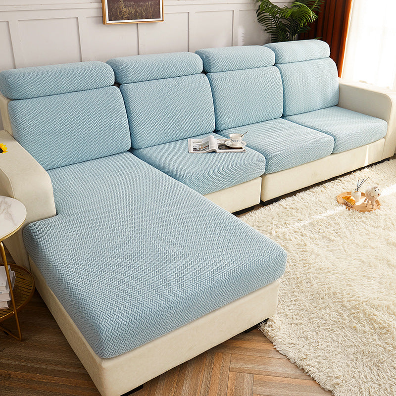 A light blue textured sofa cushion set fitted onto an L-shaped sectional sofa with cream-colored frames, shown in a styled living room setting with a white shag rug and wood flooring.