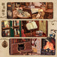 Detailed wooden model of a room with books, furniture, and decorative items.