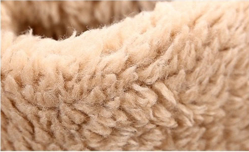Close-up of a soft, plush fleece fabric in a warm beige or cream color, showing the textured looped pile.