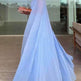 Woman wearing a light blue dress in an indoor setting with a cityscape view.