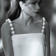 Black and white photo of a woman wearing a strapless dress with pearl straps.