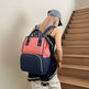 Person wearing a pink and blue backpack walking up a wooden staircase.