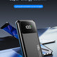 A black portable power bank with a digital display showing 100% battery level, standing upright in front of laptops and a tablet on a dark blue surface. Text at the top reads '140W Two-way fast charging super-energy column' and 'Laptop/phone/tablet can be charged'.