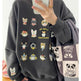 Person wearing a dark gray sweatshirt with cat illustrations, holding a phone.