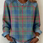 Person wearing a plaid shirt with denim sleeves against a neutral background