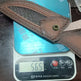 Brown leather belt with a metal buckle on a digital scale displaying weight.
