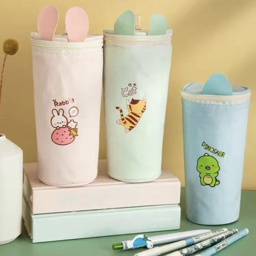 Three cute pencil cases with animal illustrations on a green surface.