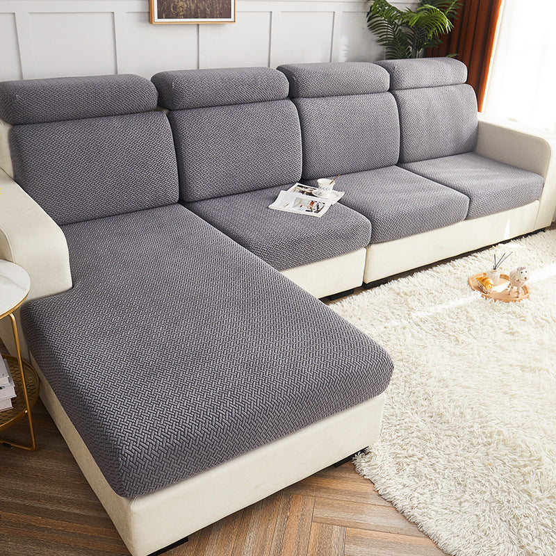 Gray sectional sofa in a living room setting with a white rug and wooden floor.
