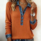 Person wearing an orange sweater with denim collar and cuffs on a plain background