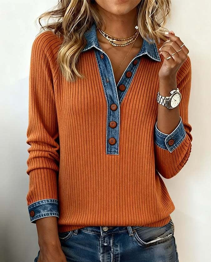 Person wearing an orange sweater with denim collar and cuffs on a plain background