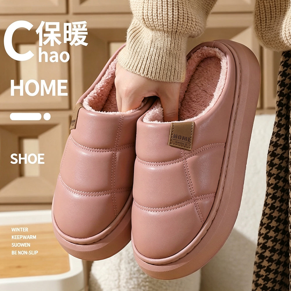 A person holds up a pair of pink quilted slip-on house slippers with a soft fleece lining. The image includes text overlays reading 'HOME SHOE' and 'WINTER KEEP WARM SLIPON BE NON-SLIP'.