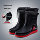 Black rain boots with red soles on a gray background
