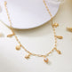 Gold necklace with shell and pearl charms on a white surface