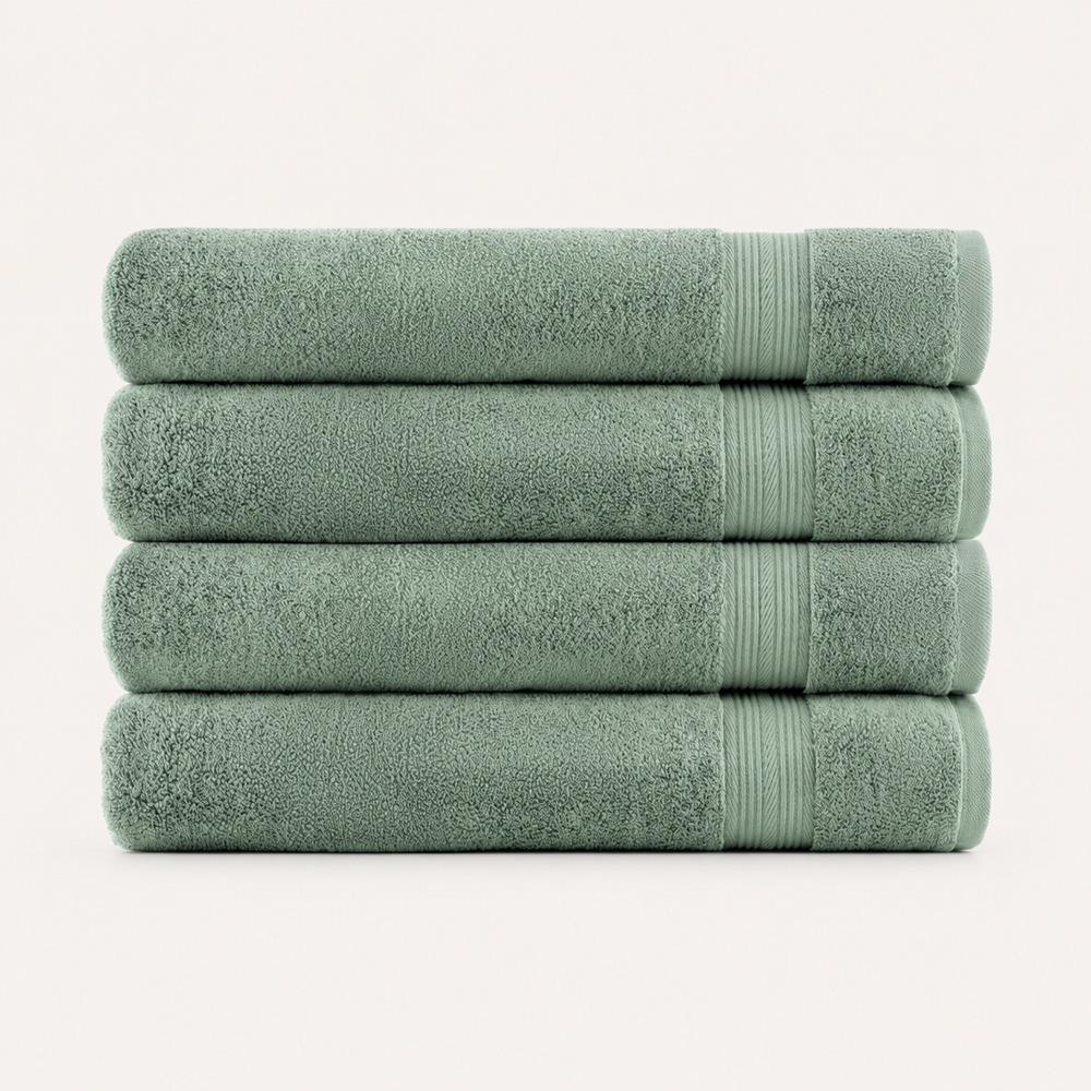 Four folded towels stacked vertically, made of soft textured fabric in a muted sage green color, set against a plain off-white background.